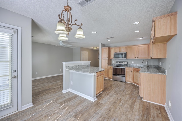 kitchen with stainless steel appliances, visible vents, light brown cabinetry, and light wood finished floors