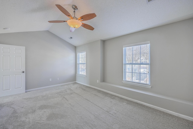 empty room with a ceiling fan, a textured ceiling, carpet floors, baseboards, and vaulted ceiling