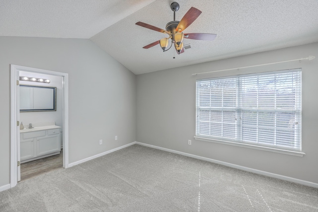 unfurnished bedroom featuring a textured ceiling, vaulted ceiling, and light carpet