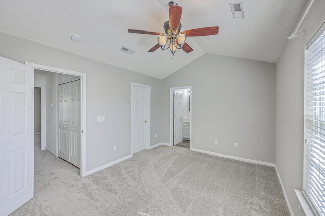 unfurnished bedroom with light carpet, visible vents, baseboards, and vaulted ceiling