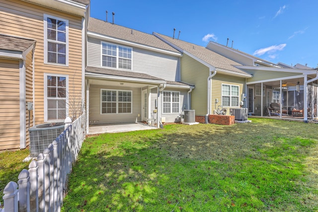 rear view of house with a patio area, cooling unit, and a lawn