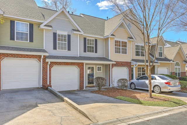 view of property with brick siding, driveway, an attached garage, and roof with shingles