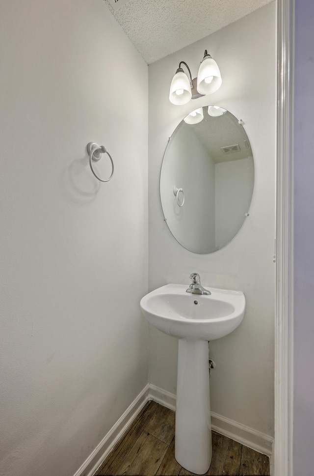 bathroom with visible vents, a textured ceiling, baseboards, and wood finished floors