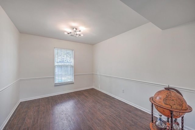 unfurnished room featuring baseboards, a chandelier, and wood finished floors