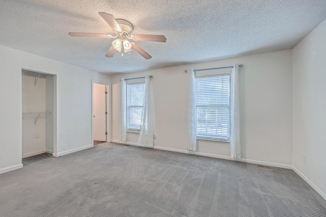 carpeted spare room with a textured ceiling, baseboards, and a ceiling fan