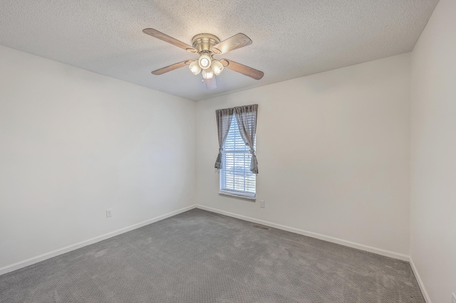 empty room featuring dark colored carpet, visible vents, ceiling fan, and baseboards