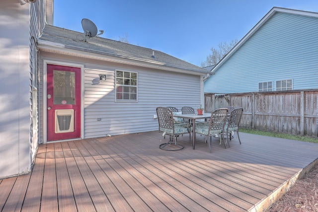 wooden terrace with outdoor dining space, elevator, and fence