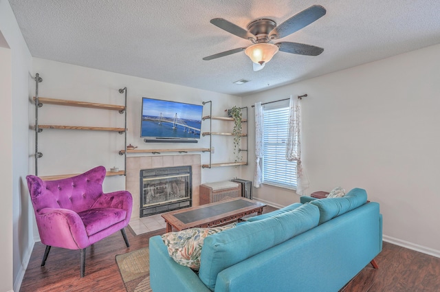 living room with a fireplace, ceiling fan, a textured ceiling, wood finished floors, and baseboards