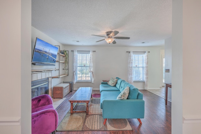 living room featuring a textured ceiling, ceiling fan, a fireplace, wood finished floors, and visible vents