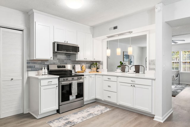kitchen with appliances with stainless steel finishes, tasteful backsplash, light wood-type flooring, light countertops, and a textured ceiling