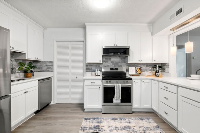 kitchen with appliances with stainless steel finishes, decorative backsplash, light countertops, and a textured ceiling