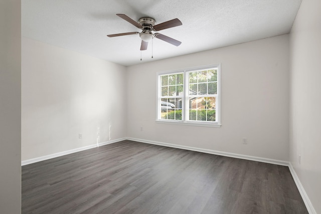 empty room featuring dark wood-type flooring, a ceiling fan, and baseboards