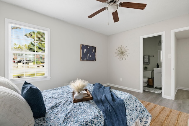 bedroom with wood finished floors, baseboards, ensuite bathroom, and a ceiling fan