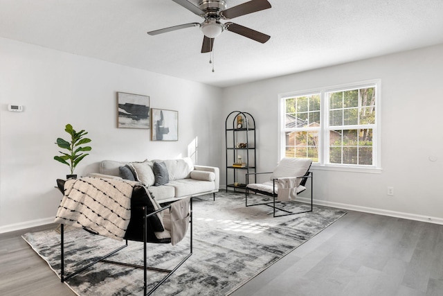 living area with a ceiling fan, wood finished floors, and baseboards