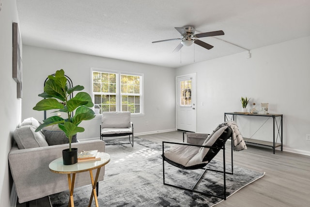 living area with wood finished floors, ceiling fan, and baseboards