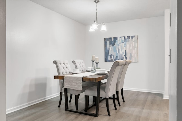 dining space with wood finished floors, baseboards, and a chandelier