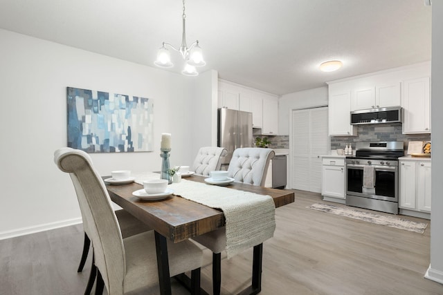 dining space with a chandelier, light wood-style flooring, and baseboards