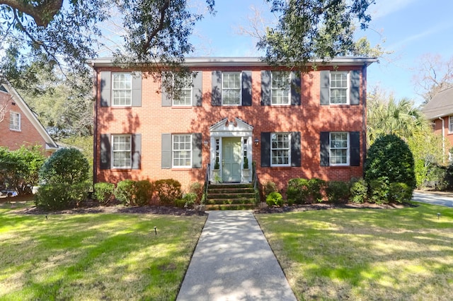 colonial house featuring brick siding and a front lawn