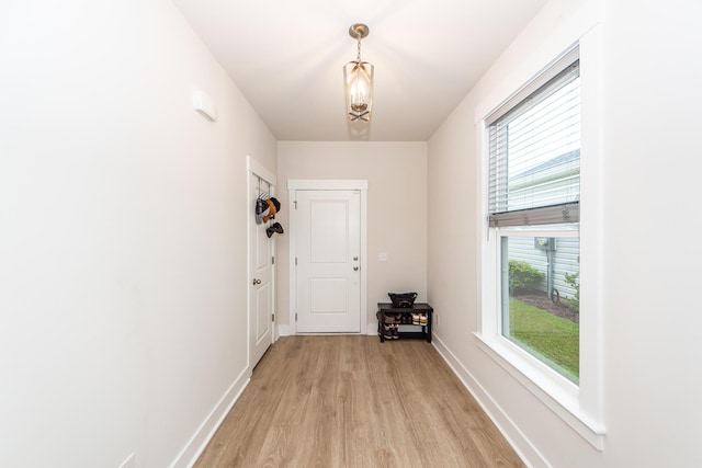 doorway featuring light wood-type flooring, an inviting chandelier, and plenty of natural light