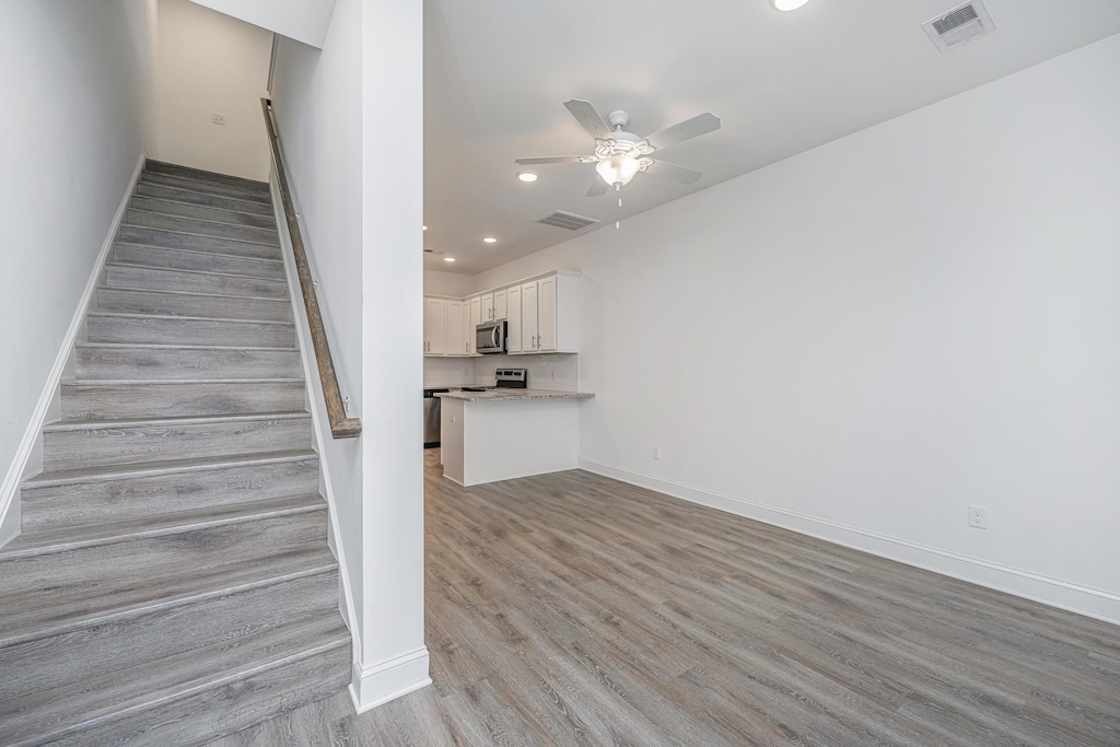 stairway featuring ceiling fan and wood-type flooring