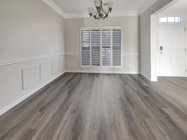 unfurnished dining area featuring dark hardwood / wood-style flooring, crown molding, and an inviting chandelier