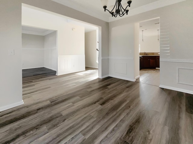 unfurnished dining area featuring dark wood-type flooring, a notable chandelier, and ornamental molding