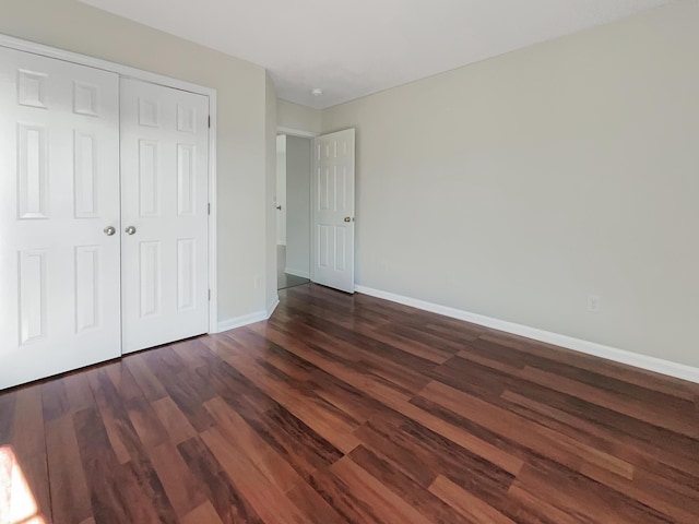 unfurnished bedroom featuring a closet and dark wood-type flooring