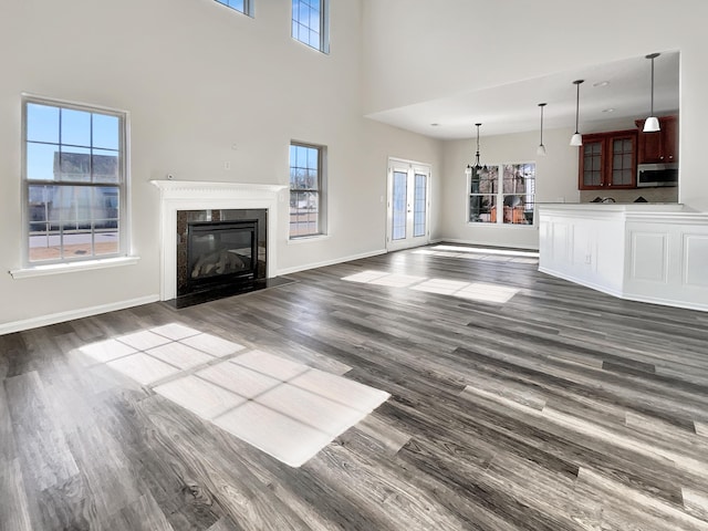 unfurnished living room featuring a fireplace, french doors, a high ceiling, and dark hardwood / wood-style flooring