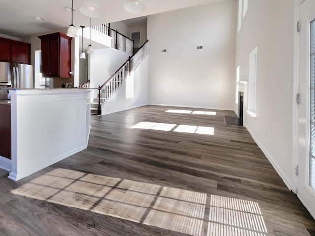 kitchen featuring pendant lighting, dark hardwood / wood-style flooring, a towering ceiling, stainless steel fridge with ice dispenser, and a wealth of natural light