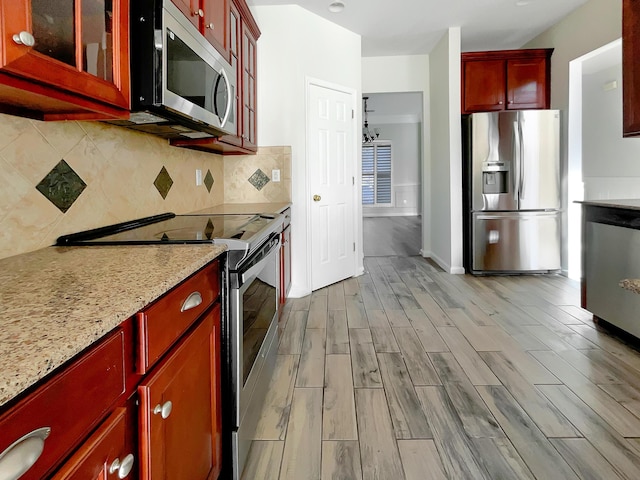 kitchen with decorative backsplash, light stone countertops, and appliances with stainless steel finishes