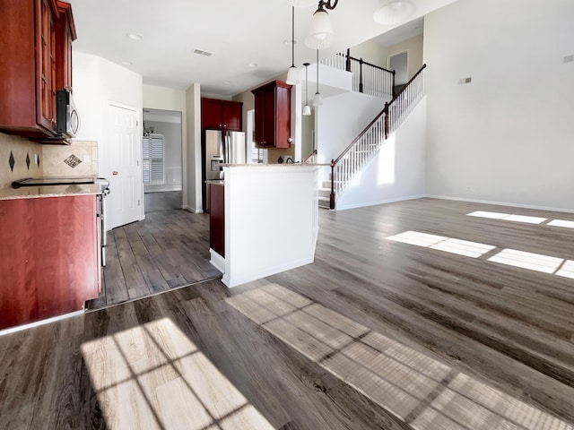 kitchen featuring backsplash, dark wood-type flooring, pendant lighting, and stainless steel appliances