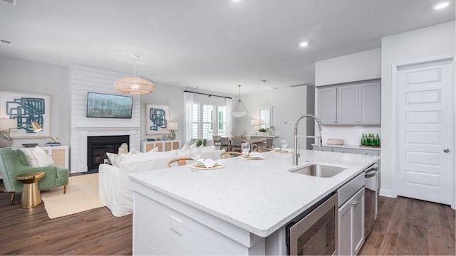 kitchen with pendant lighting, a kitchen island with sink, sink, and gray cabinetry