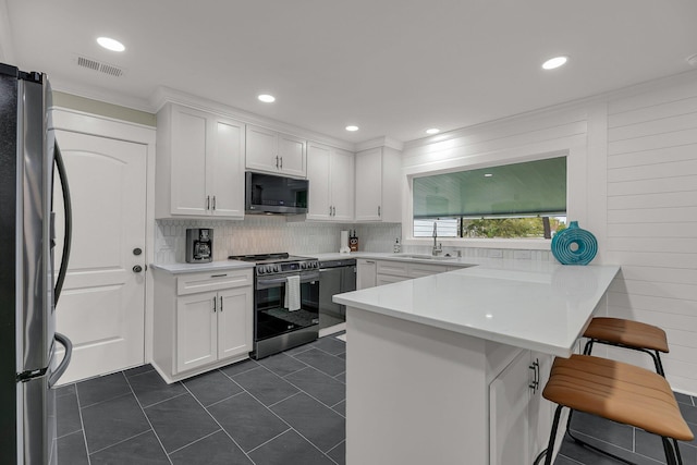 kitchen featuring sink, a kitchen breakfast bar, kitchen peninsula, white cabinets, and appliances with stainless steel finishes