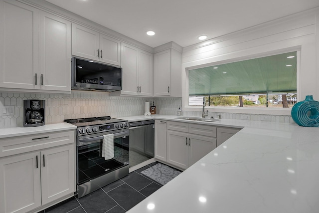 kitchen with dark tile patterned floors, white cabinetry, sink, and appliances with stainless steel finishes