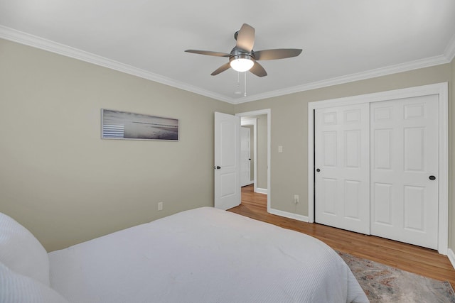 bedroom featuring ceiling fan, wood-type flooring, crown molding, and a closet