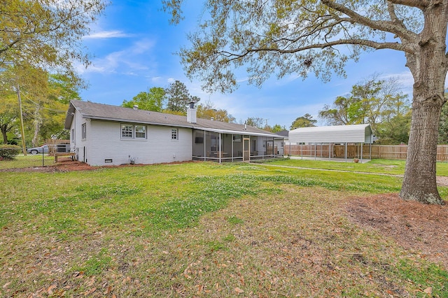 rear view of property featuring a sunroom, a carport, and a lawn