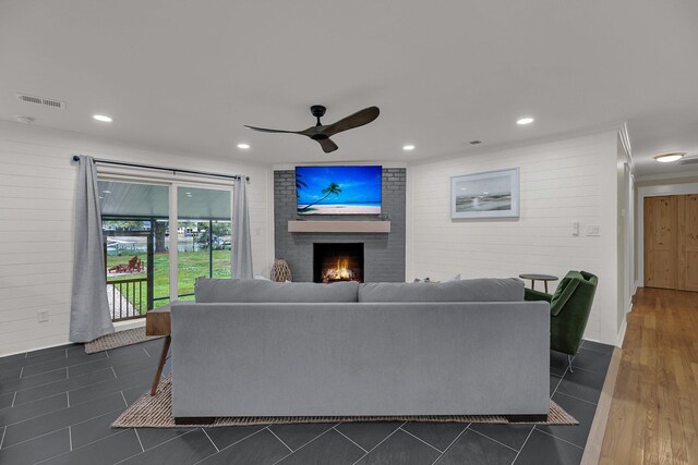 living room with ceiling fan, dark hardwood / wood-style floors, and a brick fireplace