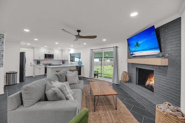 living room with ceiling fan, crown molding, dark tile patterned floors, and a fireplace