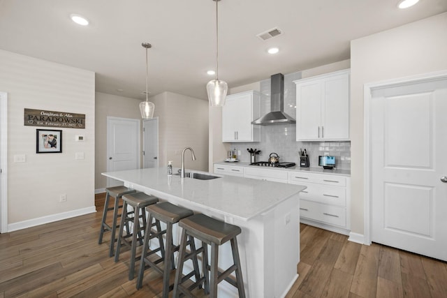 291 Lucca Dr, Summerville, SC 29486 - kitchen with wall chimney range hood, an island with sink, stainless steel gas cooktop, white cabinets, and backsplash