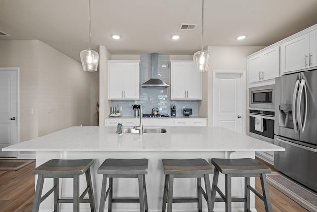 291 Lucca Dr, Summerville, SC 29486 - kitchen featuring wall chimney range hood, stainless steel appliances, backsplash, white cabinets, and a kitchen breakfast bar
