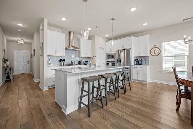 291 Lucca Dr, Summerville, SC 29486 - kitchen with wall chimney range hood, appliances with stainless steel finishes, tasteful backsplash, a kitchen breakfast bar, and an island with sink