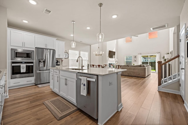 291 Lucca Dr, Summerville, SC 29486 - kitchen featuring stainless steel appliances, light countertops, white cabinets, light wood-style flooring, and recessed lighting