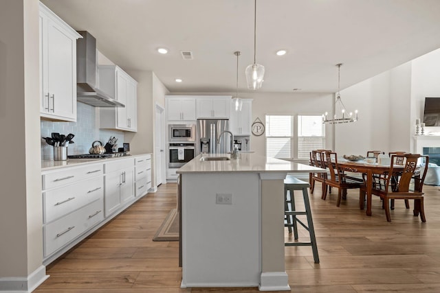 291 Lucca Dr, Summerville, SC 29486 - kitchen featuring wall chimney exhaust hood, stainless steel appliances, a breakfast bar area, decorative backsplash, and a kitchen island with sink
