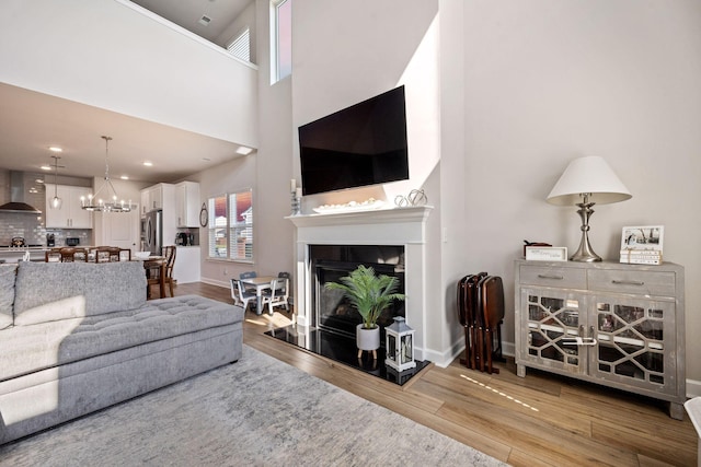291 Lucca Dr, Summerville, SC 29486 - living area with wood finished floors, a fireplace, a chandelier, and a towering ceiling
