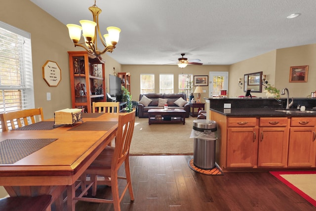 dining area with ceiling fan with notable chandelier, dark hardwood / wood-style floors, sink, and a textured ceiling