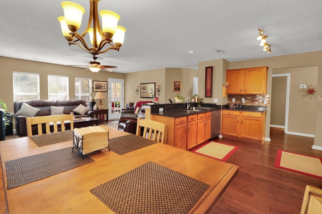 dining area featuring sink, ceiling fan with notable chandelier, dark wood-type flooring, and a textured ceiling