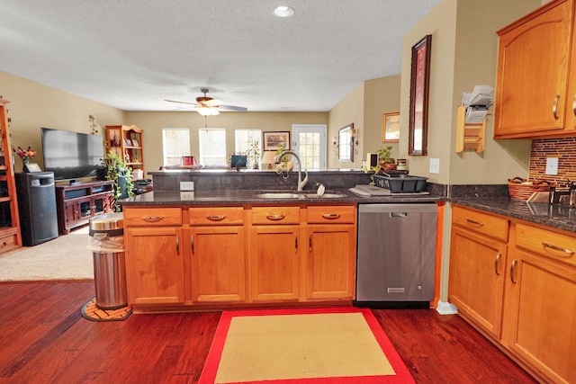 kitchen featuring sink, stainless steel dishwasher, dark hardwood / wood-style flooring, kitchen peninsula, and dark stone counters