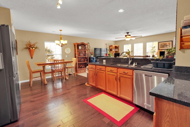 kitchen featuring stainless steel appliances, sink, dark wood-type flooring, and decorative light fixtures