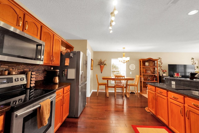 kitchen with pendant lighting, stainless steel appliances, tasteful backsplash, a textured ceiling, and dark hardwood / wood-style flooring