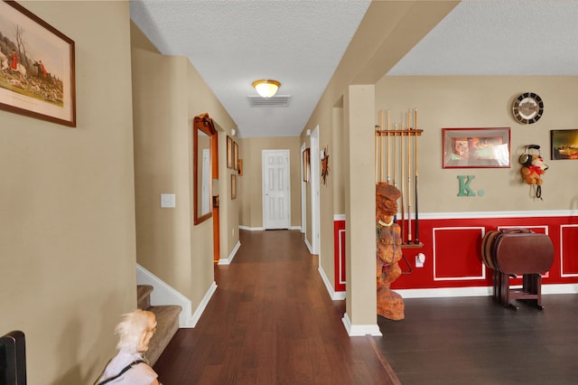 corridor with a textured ceiling and dark hardwood / wood-style flooring